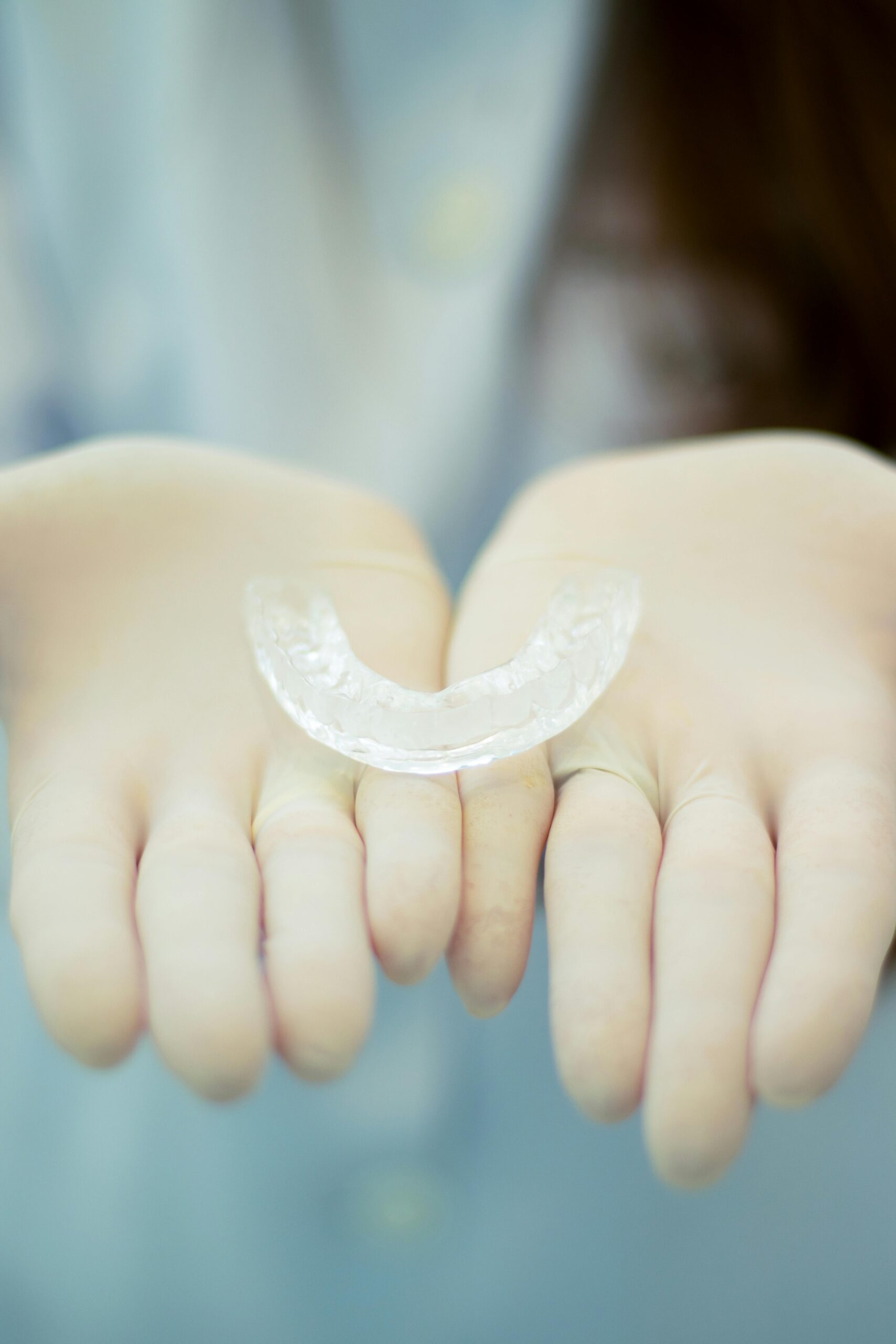 Clear orthodontic retainer held in hands Markham dentist